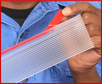 Photo showing a finger peeling the red 3M-VHB film liner from transparent adhesive on a "Univerally Adjustable - Shower Door Drip Rail".